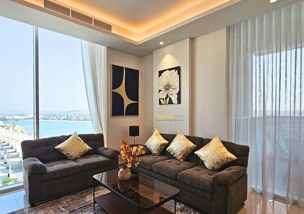 A modern living room with two sofas, a coffee table, and artwork on the walls. - Luxurious Waterfront 2-Bedroom Apartment in RAK (Al Riffa)