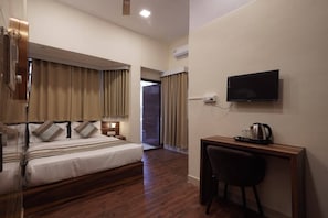 A hotel room with a bed, a desk, a chair, a television, and an air conditioning unit. - Imperial Palace (Bengaluru)