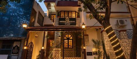 A hotel entrance with a sign for 'Imperial Jenukal Suites' and a staircase leading to the entrance.