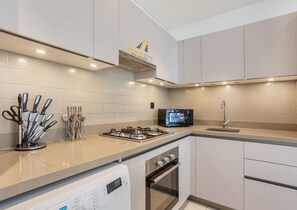 A modern kitchen with a gas stove, microwave, oven, and a dishwasher. - Beautiful 2BR Sobha Hartland | Near Dubai Mall (Dubai)