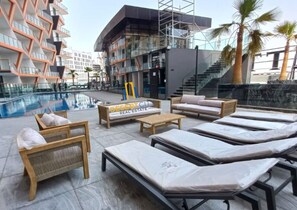A rooftop pool area with lounge chairs and a magazine stand. - 8 mins to Downtown / King Bed / 5F (Dubai)