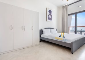 Une chambre à coucher moderne, avec un lit, une armoire et une grande fenêtre.