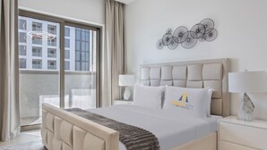 A hotel room with a large bed, a view of the city, and a decorative wall piece. - Peaceful Location | All Bills Included (Dubai)