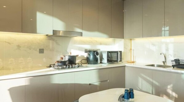 A modern kitchen with a marble backsplash, stainless steel appliances, and a minimalist design. - Comfortable 1BR with City Access | Azizi Farhad (Dubai)