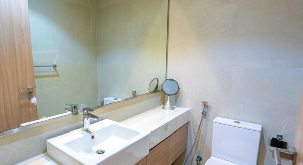 Un baño con lavamanos blanco, un espejo y un inodoro.