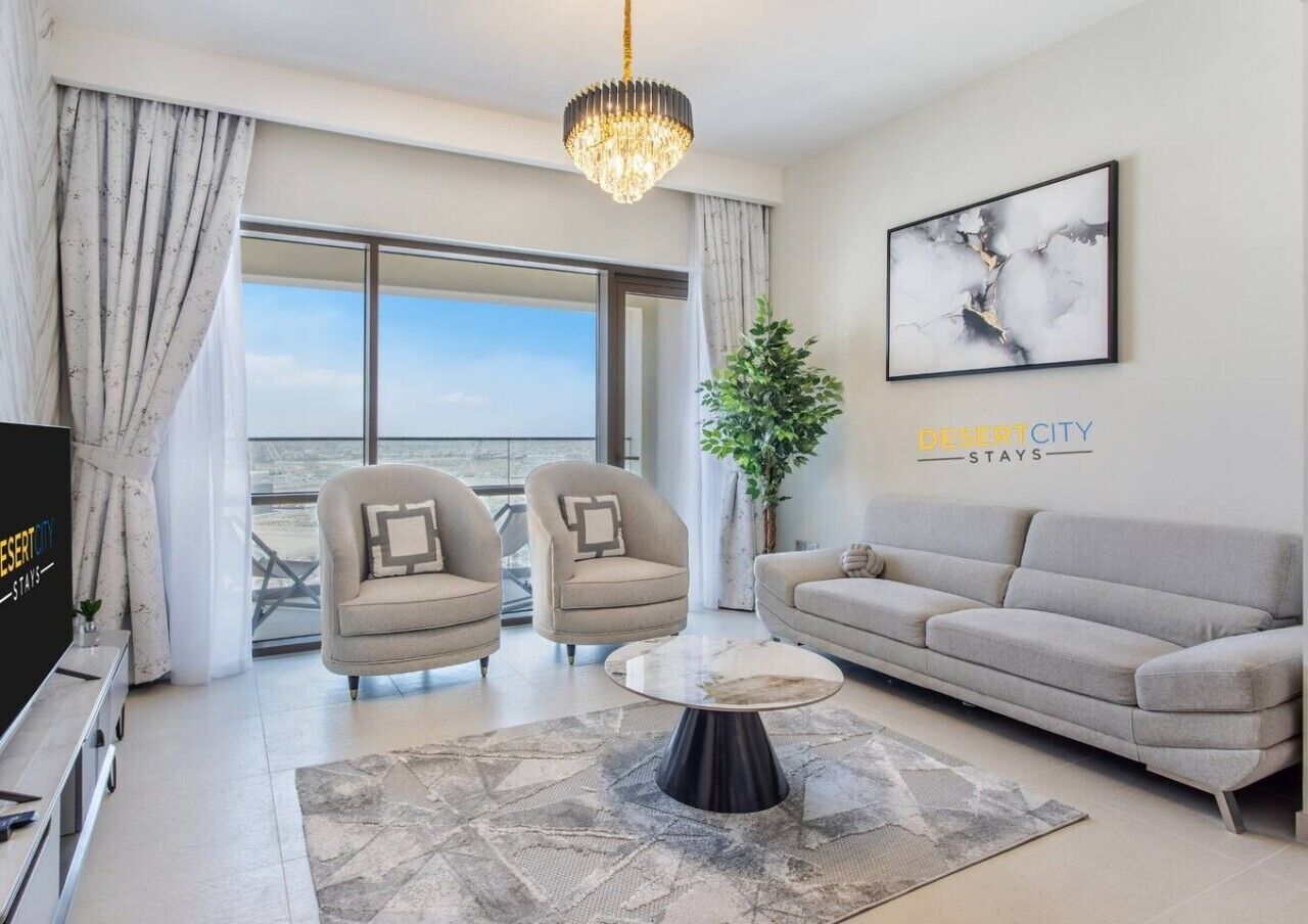 A modern living room with a sofa, two armchairs, a coffee table, and a large window offering a view.