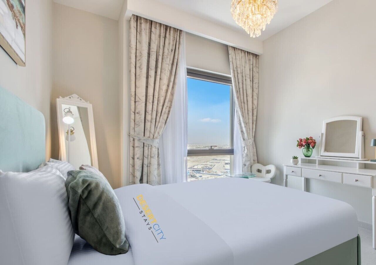 A hotel room with a bed, a desk, a chair, a mirror, and a window with a view.
