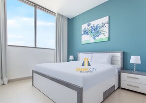 A modern bedroom with a large bed, a nightstand, a lamp, and a painting on the wall. - Restaurants nearby | Supermarket 5 mins away. (Dubai)