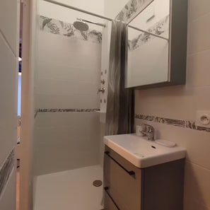 A bathroom with a shower, a sink, and a mirror. - Small studio apartment right in the heart of downtown Meaux, with the train station less than a 10-minute walk away (Meaux)