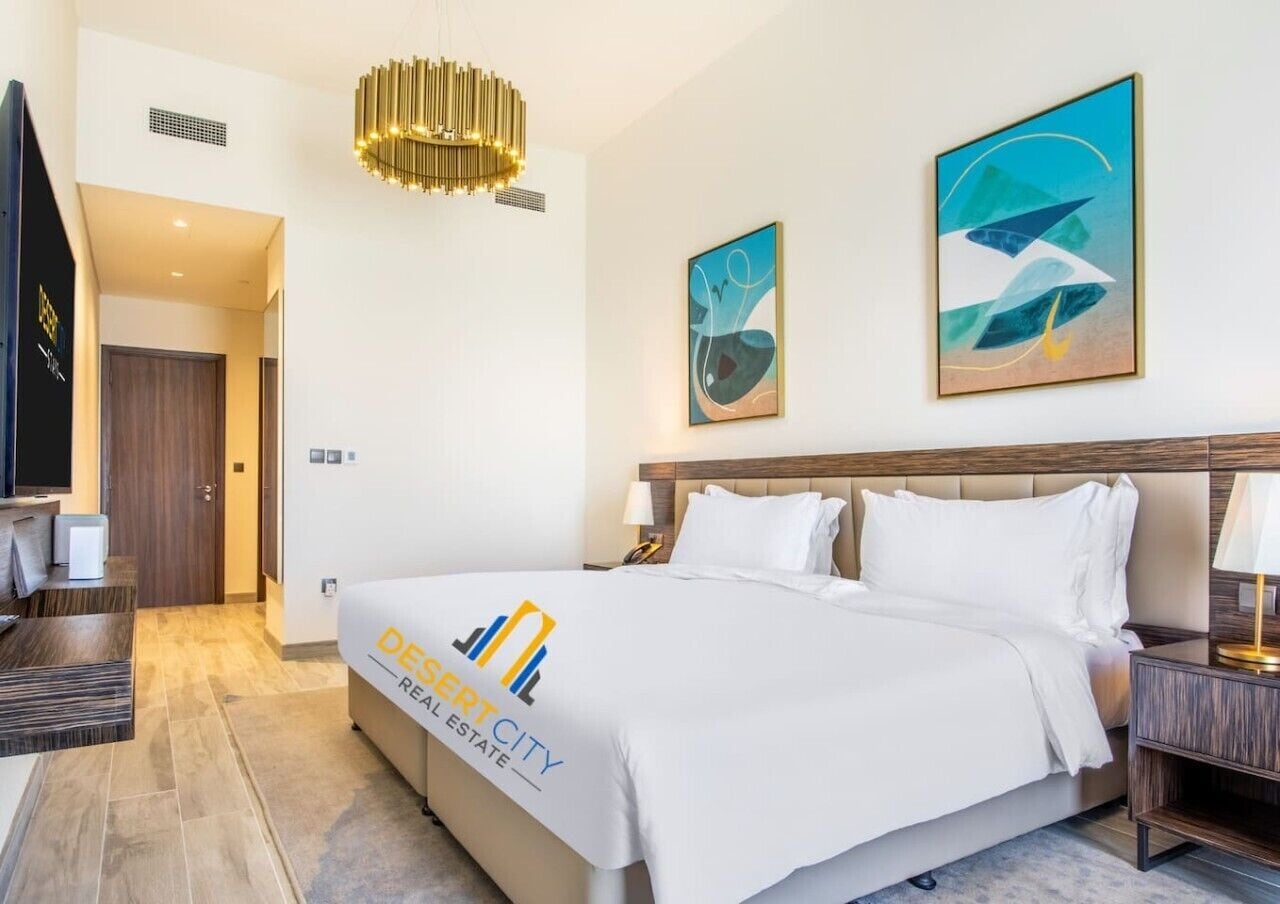 Une chambre d’hôtel équipée d’un lit, d’une télévision, d’un bureau et décorée avec des œuvres d’art.