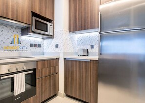 A modern kitchen with stainless steel appliances, wooden cabinets, and a patterned backsplash. - High-end 2BR near Palm Jumeirah/ Dubai Marina/ JBR (Dubai)