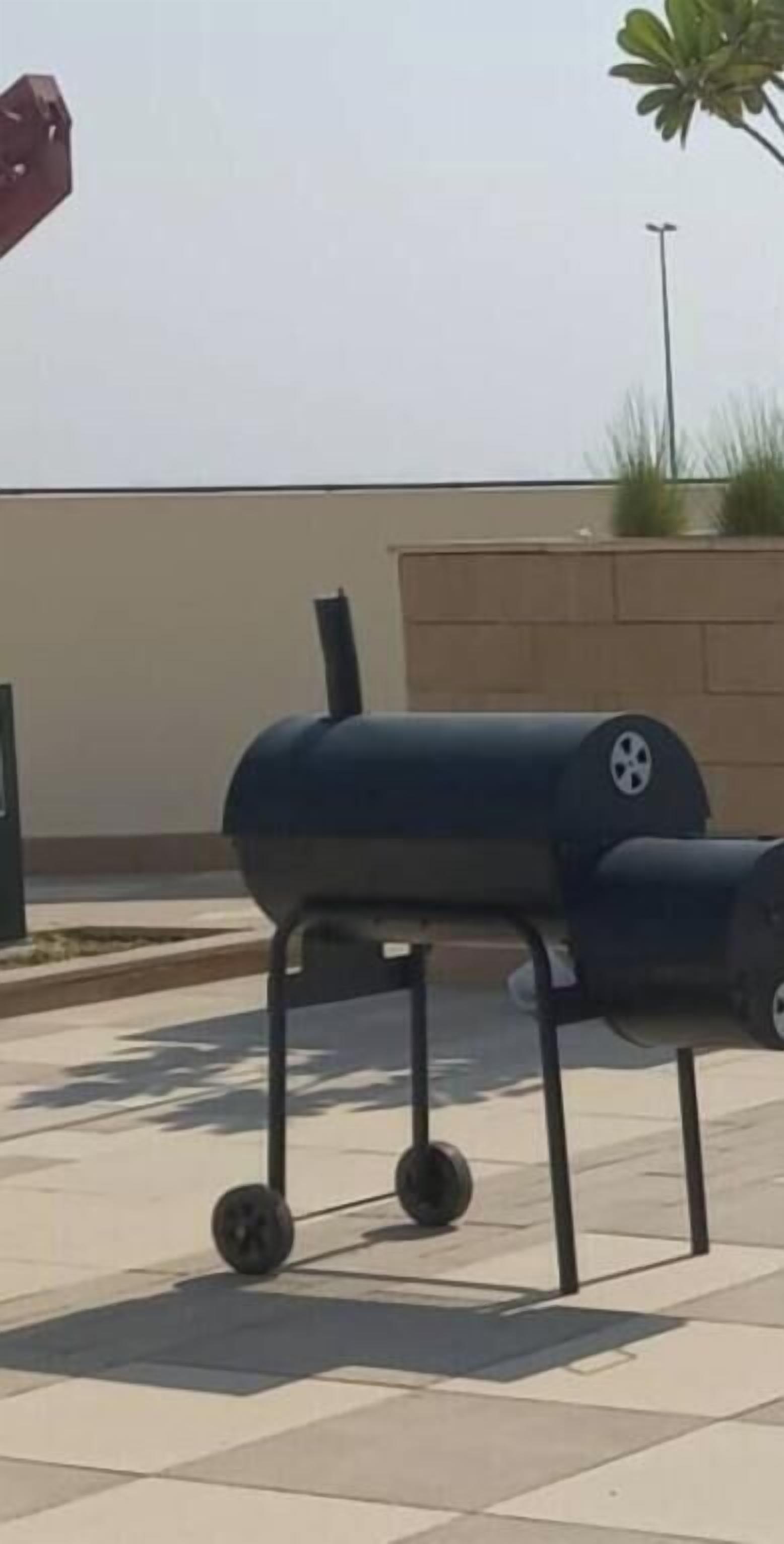 A portable barbecue grill on a tiled patio.
