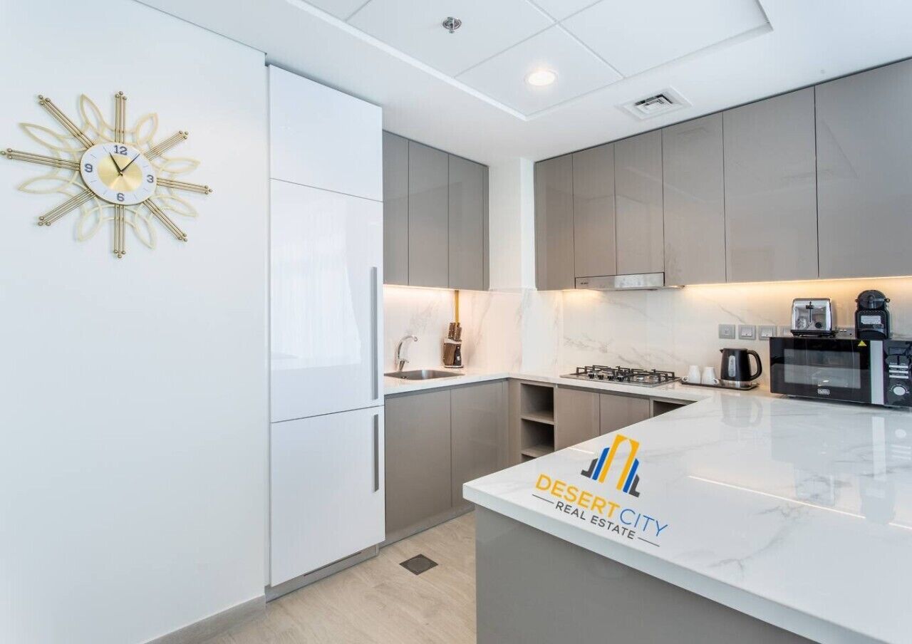 A modern kitchen with white cabinetry, a central island, and a decorative wall clock.