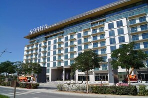 A multi-story hotel with a prominent 'SOBHA' sign, featuring a modern architectural design with large windows and a flat roof. - 1 BR Sobha Hartland | Fast WiFi | Near Downtown (Dubai)
