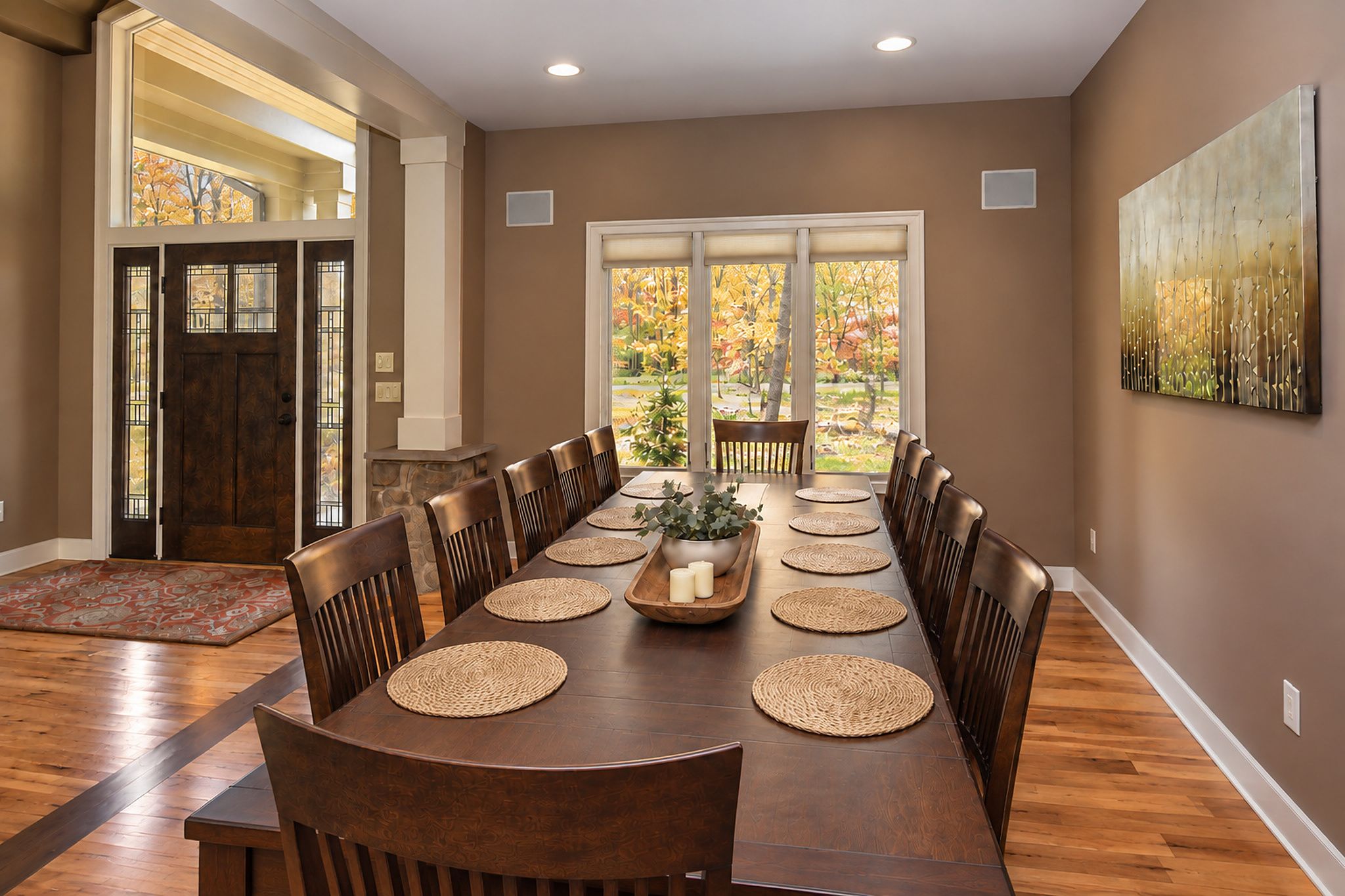 Une salle à manger avec une longue table, des chaises et une vue à travers les portes vitrées.