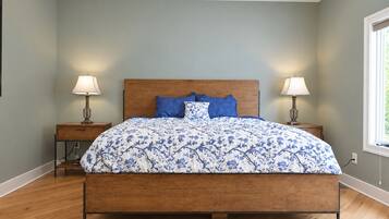 A bedroom with a wooden bed, two bedside tables with lamps, a window, and a ceiling fan.