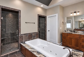 A modern bathroom with a large bathtub, a walk-in shower, and a vanity with a mirror.