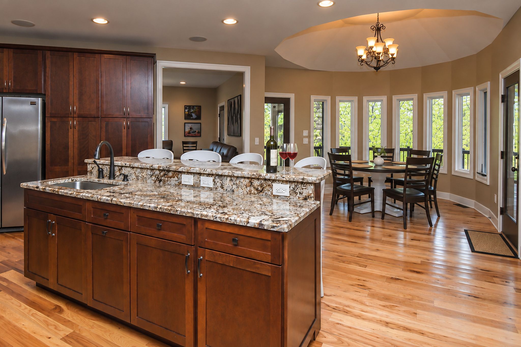 A kitchen with wooden cabinets, a granite countertop, and a dining area with a table and chairs.