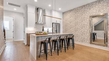 A modern kitchen with a central island, bar stools, and a patterned wallpaper.