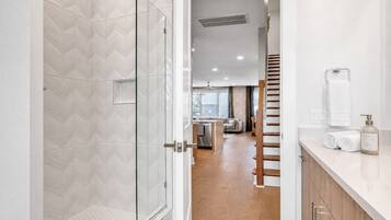 A modern bathroom with a glass shower door, a toilet, and a sink with a towel and soap dispenser.