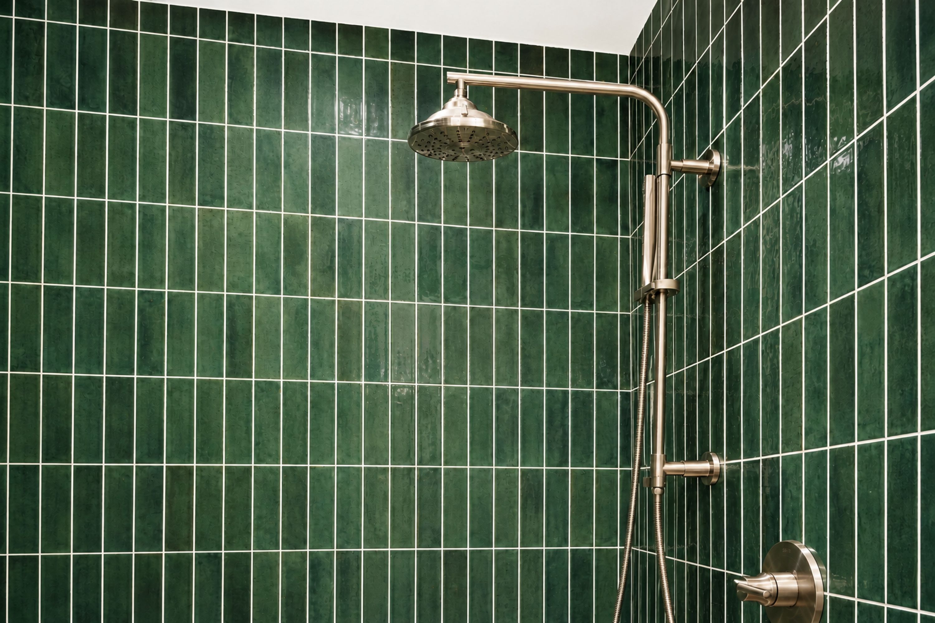 Ducha con cabezal de ducha de mano y llave de control en la pared.