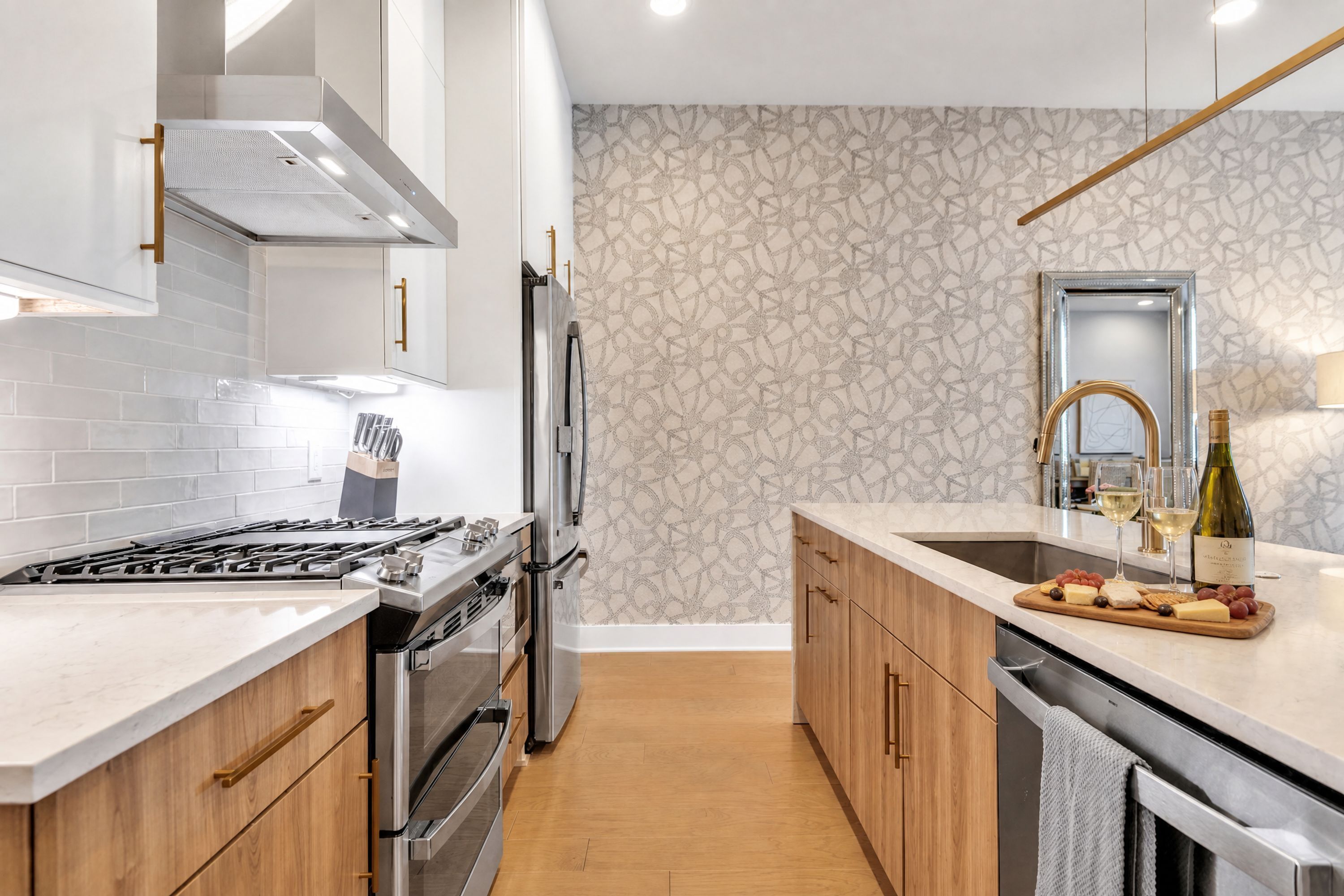 Una cocina moderna con estufa de acero inoxidable, horno empotrado, pileta doble y alacenas de madera.