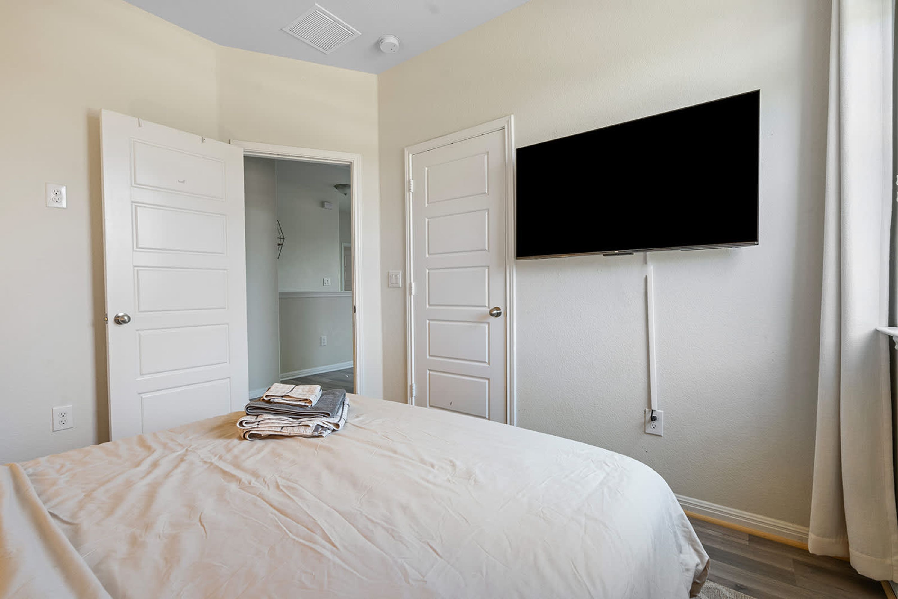 A bedroom with a bed, a TV mounted on the wall, and an open closet.