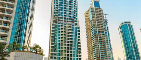 Un immeuble de grande hauteur, sur lequel on peut voir une enseigne bien visible indiquant « Résidence au bord du lac », avec une architecture moderne caractérisée par une façade à motifs géométriques de fenêtres et de balcons.