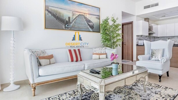 Un salon moderne avec un canapé, une table basse et un fauteuil. Il y a un tableau accroché au mur et une plante posée sur le sol.