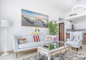 Un salon moderne avec un canapé, une table basse et un fauteuil. Il y a un tableau accroché au mur et une plante posée sur le sol.