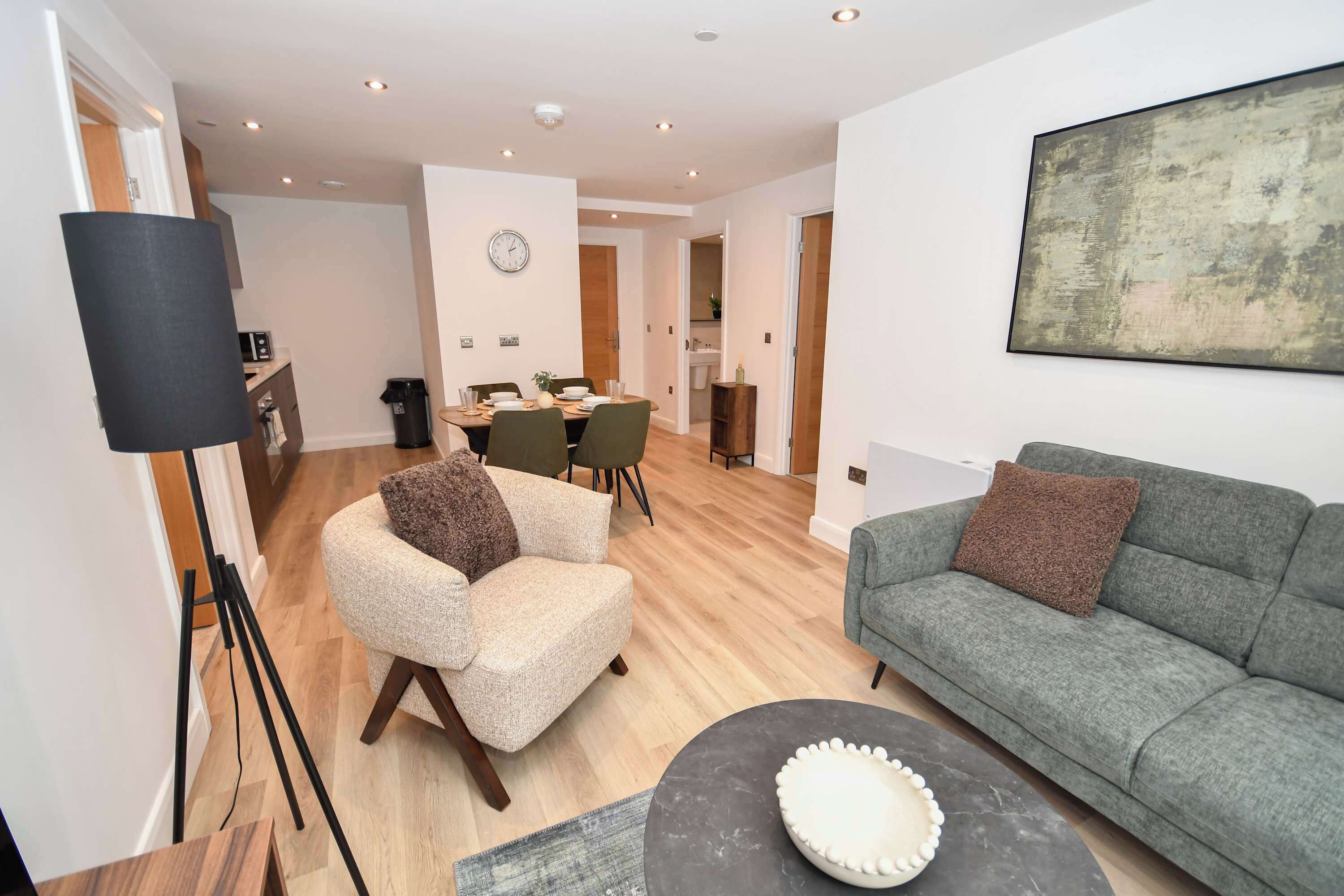 A modern living room with a grey sofa, a beige armchair, and a coffee table.