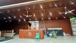 A reception area with a wooden reception desk, a green chair, and a ceiling fan.