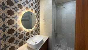 A bathroom with a white sink, a round mirror, and a shower with a glass door.
