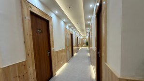 A hotel corridor with wooden doors, a carpeted floor, and recessed ceiling lighting.