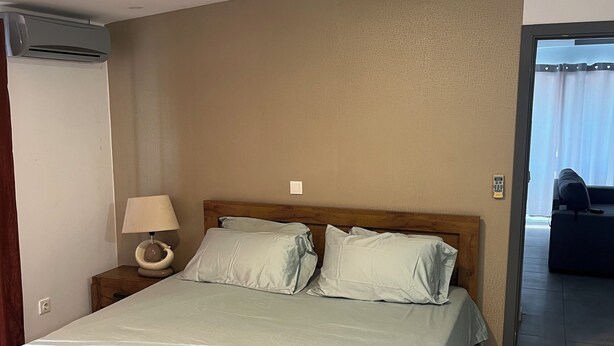 A bedroom with a bed, bedside lamp, and an air conditioning unit.