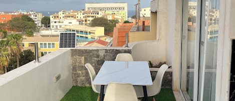 A balcony with artificial grass, a table, and chairs.