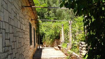 A narrow stone pathway leading to a building with a stone wall and a wooden beam overhead.