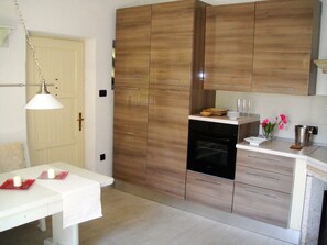 A kitchen with wooden cabinets, a white countertop, and a dining table with a white tablecloth.