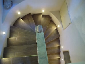 A spiral staircase with a central column and a stone sculpture at the top.