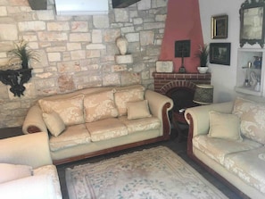 A living room with a stone wall, a fireplace, and a sofa.
