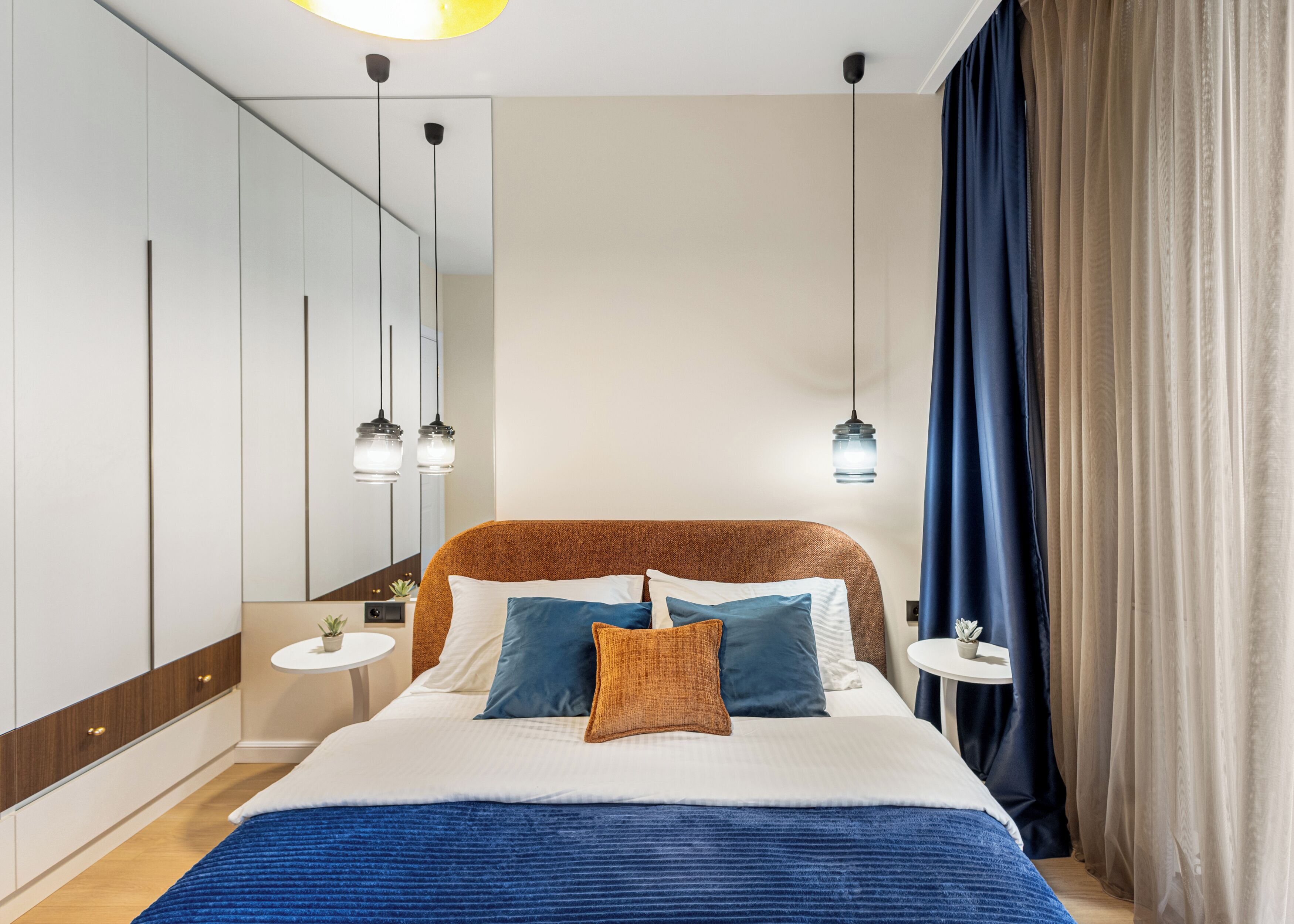 A modern bedroom with a large bed, bedside tables, and a mirror.