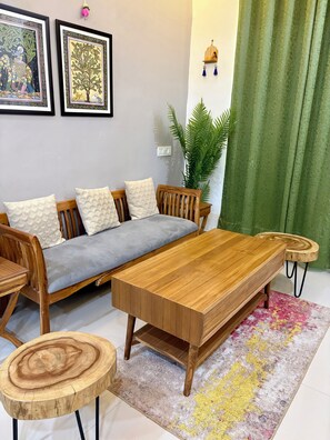 Una sala de estar con sofá, mesa de centro de madera y una planta.