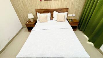 A hotel room with a large bed, two bedside tables, a nightstand, a lamp, and a picture on the wall.