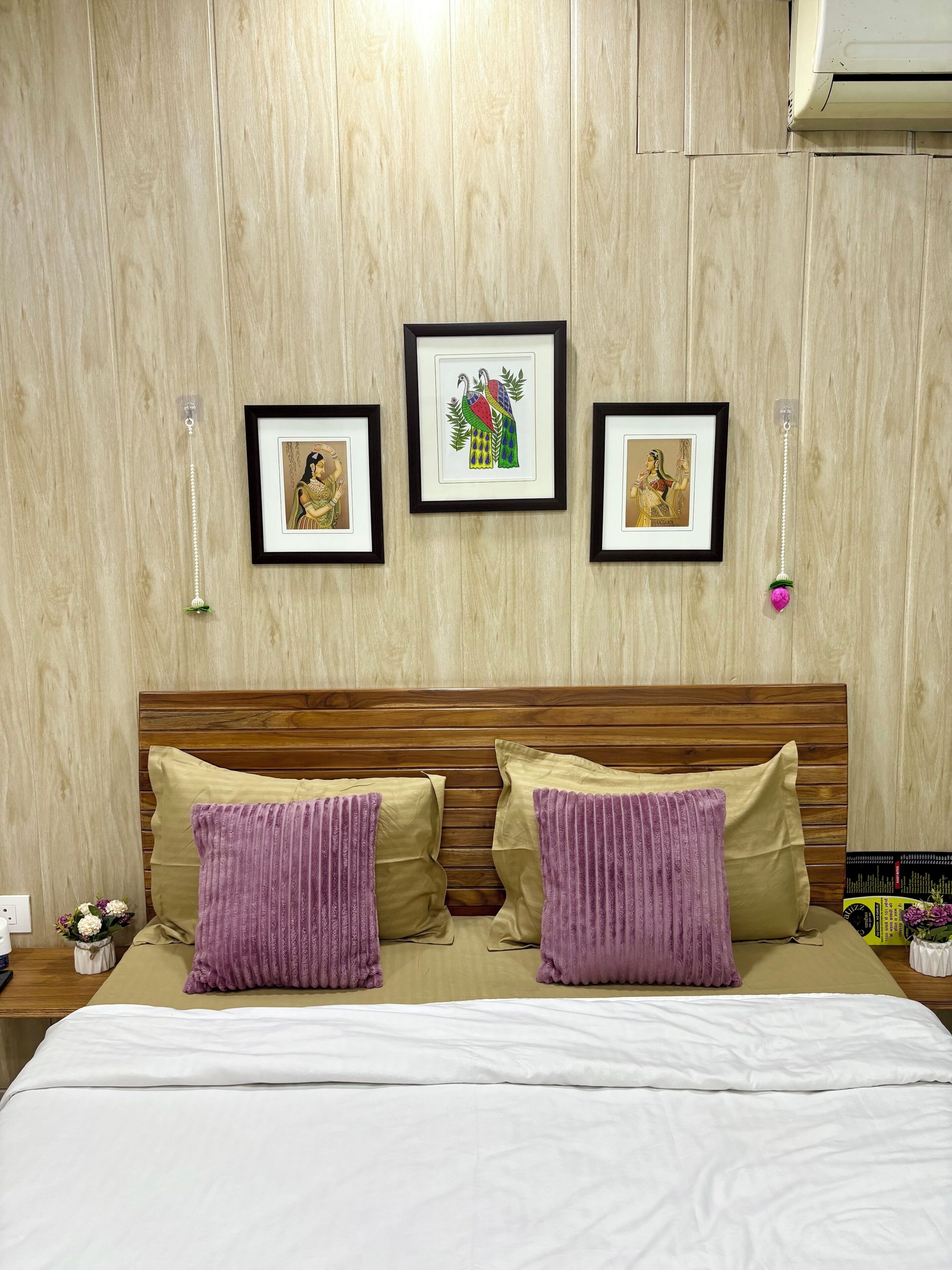 Una cama con dos almohadas, un cabecero de madera y tres cuadros en la pared.