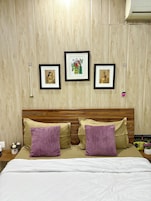 Una cama con dos almohadas, un cabecero de madera y tres cuadros en la pared.