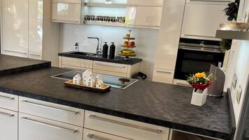 Eine moderne Küche mit schwarzer Arbeitsplatte, weißen Schränken, einem Edelstahlbackofen und einem Spülbecken mit Armatur.