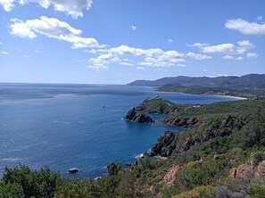 A coastal landscape with a clear sky, rocky terrain, and a view of the sea. - Ohana Residence Abba Urci Cottage (Sardegna)