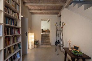 A hallway with bookshelves, a staircase, a coat rack, and a small table with a chalkboard. - The House with the Double-Glazed Window / The House of the Mullion (Sermoneta)