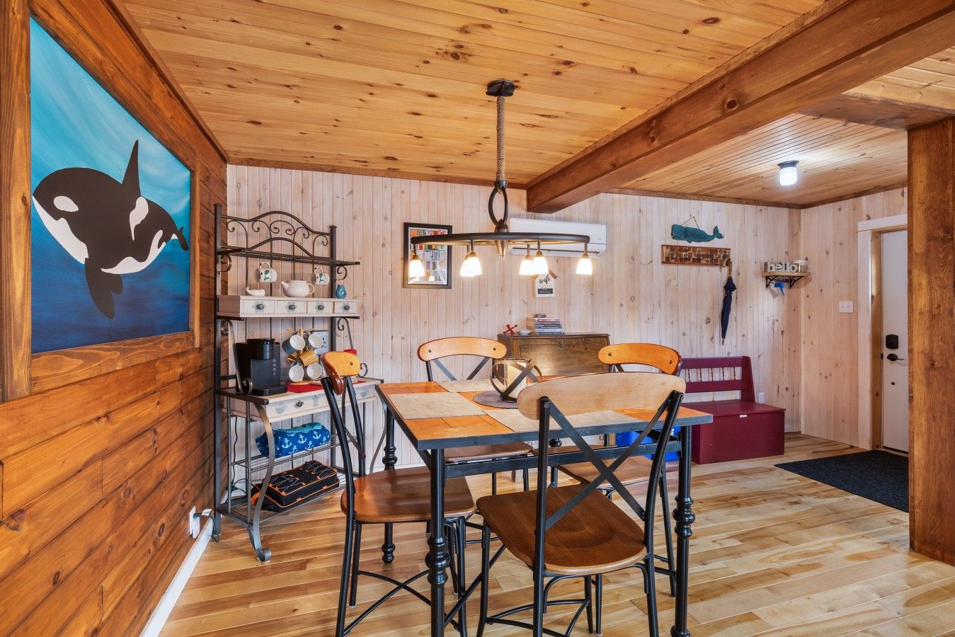 Un interior de madera con una mesa de comedor, sillas, una cafetera y una lámpara colgante.