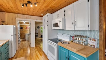 Una cocina con armarios de madera, microondas, horno y una encimera con un libro de cocina.